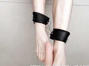 Young cuffed slave playing with his feet on dildo